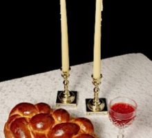 Challah, candlesticks, wine on white tablecloth